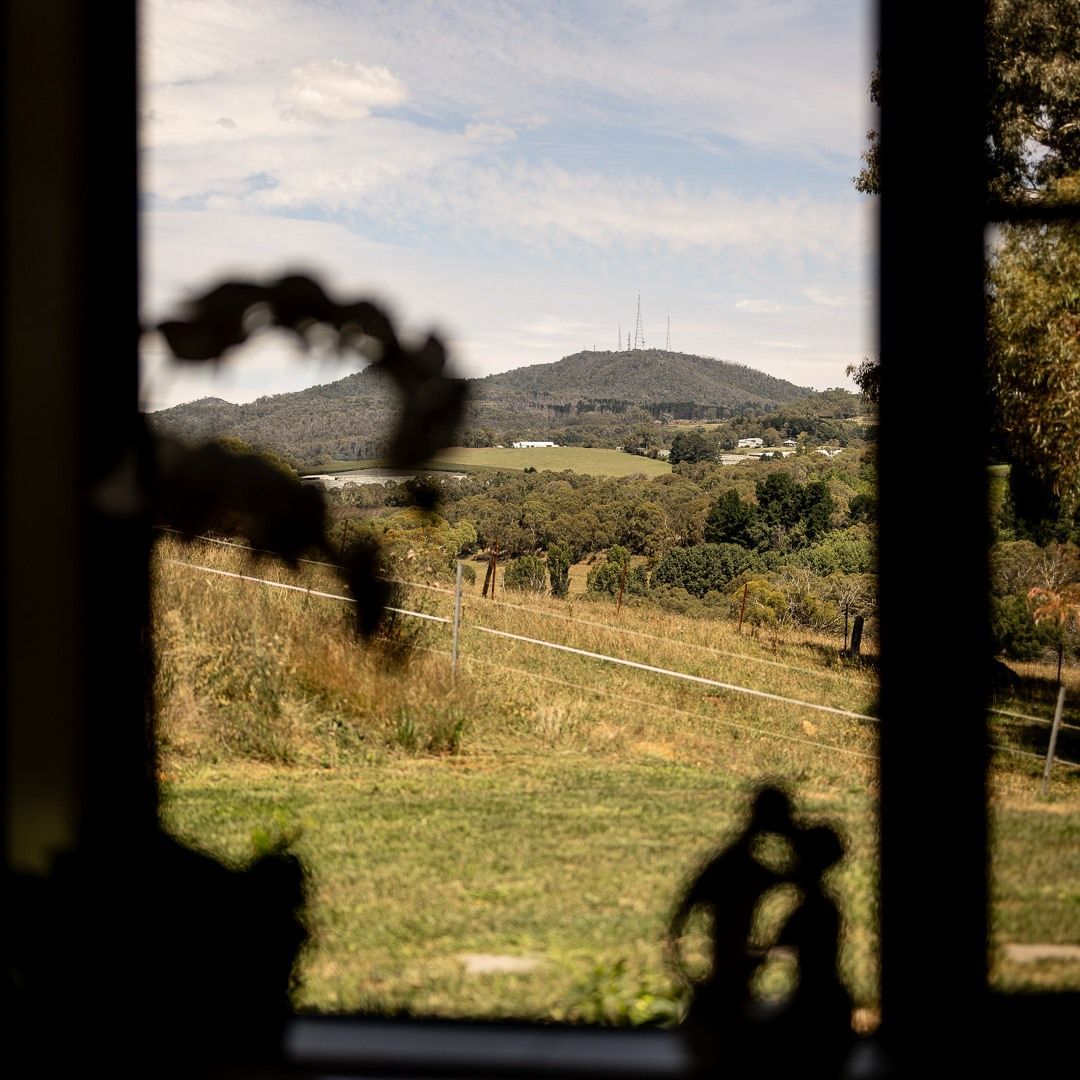 A Bedroom With a King Size Bed, Chair, Lamps and a Large Window — Lakeview Luxury Retreat in Canobolas, NSW