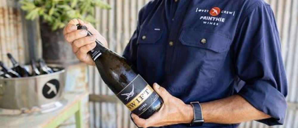 A Man in a Blue Shirt is Holding a Bottle of Wine — Lakeview Luxury Retreat in Canobolas, NSW