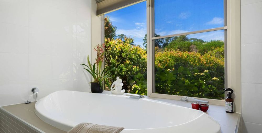 A Bathroom With a Bathtub and a Window With a View of Trees — Lakeview Luxury Retreat in Canobolas, NSW