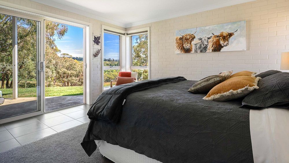 A Bedroom With a Large Bed and a Painting of Cows on the Wall — Lakeview Luxury Retreat in Canobolas, NSW