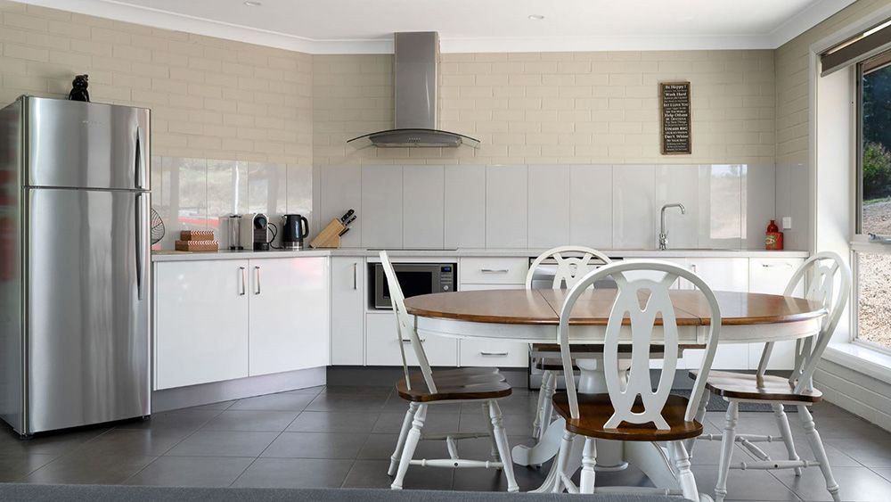 A Kitchen With a Table and Chairs and a Refrigerator — Lakeview Luxury Retreat in Canobolas, NSW