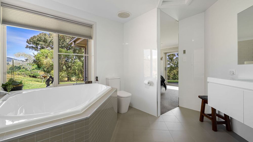 A Bathroom With a Bathtub, Toilet, Sink and Window — Lakeview Luxury Retreat in Canobolas, NSW