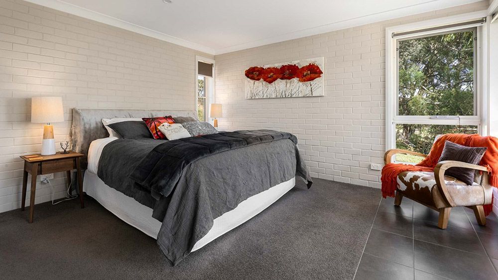 A Bedroom With a King Size Bed, Chair, Lamps and a Large Window — Lakeview Luxury Retreat in Canobolas, NSW