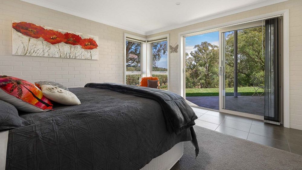 A Bedroom With a Large Bed and a Painting on the Wall — Lakeview Luxury Retreat in Canobolas, NSW