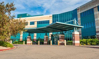 Hospital building with teal and beige exterior, covered entrance.