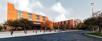 Exterior view of the La Quinta Inn, a brick building with trees in front and a cloudy sky.
