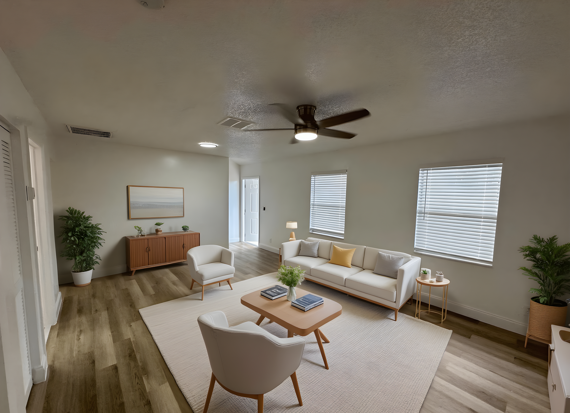 Spacious living room with a couch, armchairs, coffee table, and area rug. Neutral tones and wood flooring.