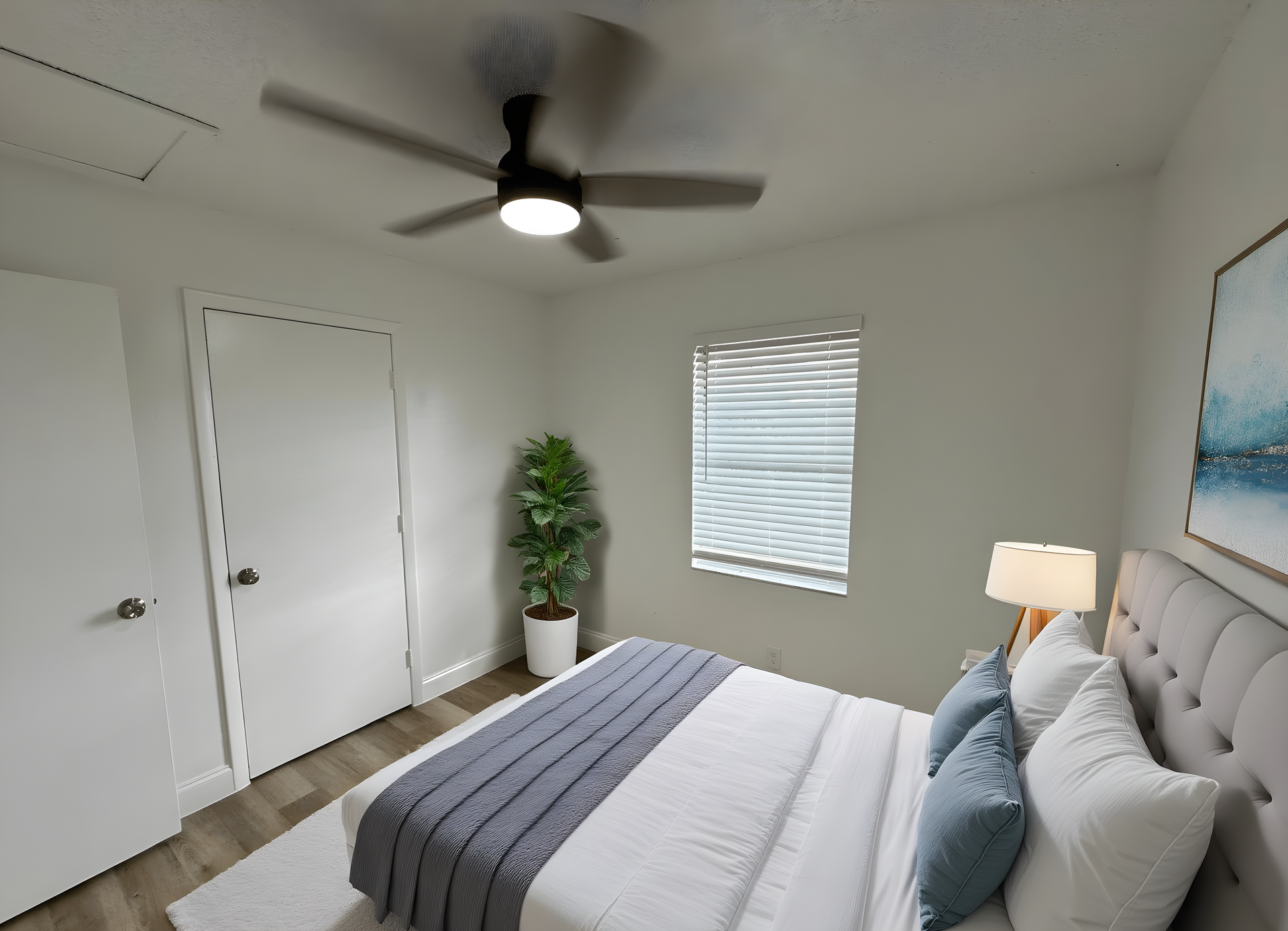 Bedroom with white walls, bed, window with blinds, ceiling fan, and a potted plant.