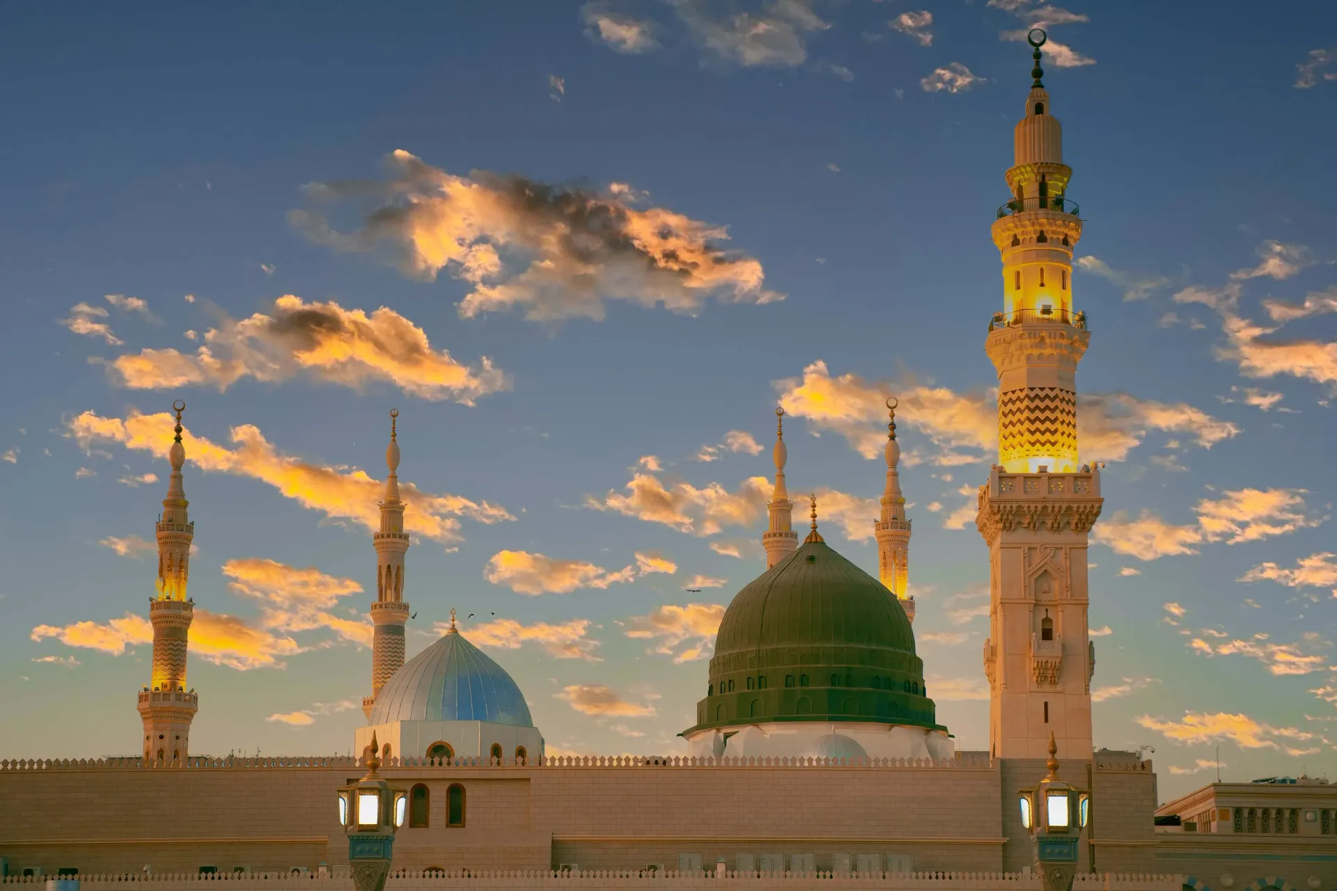 Une mosquée avec un dôme et un minaret au coucher du soleil.
