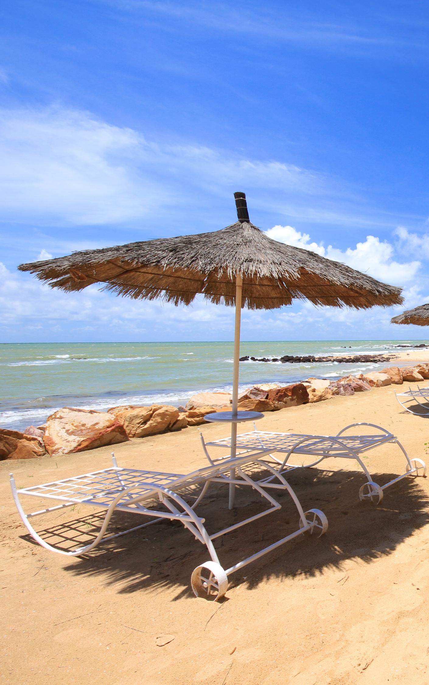 Une plage avec des chaises et un parasol par une journée ensoleillée.