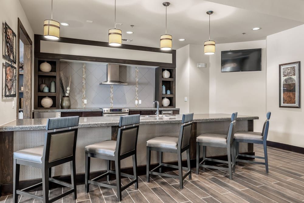 a kitchen with a long counter and chairs in it at Marquis on Lakeline in Cedar Park, TX.