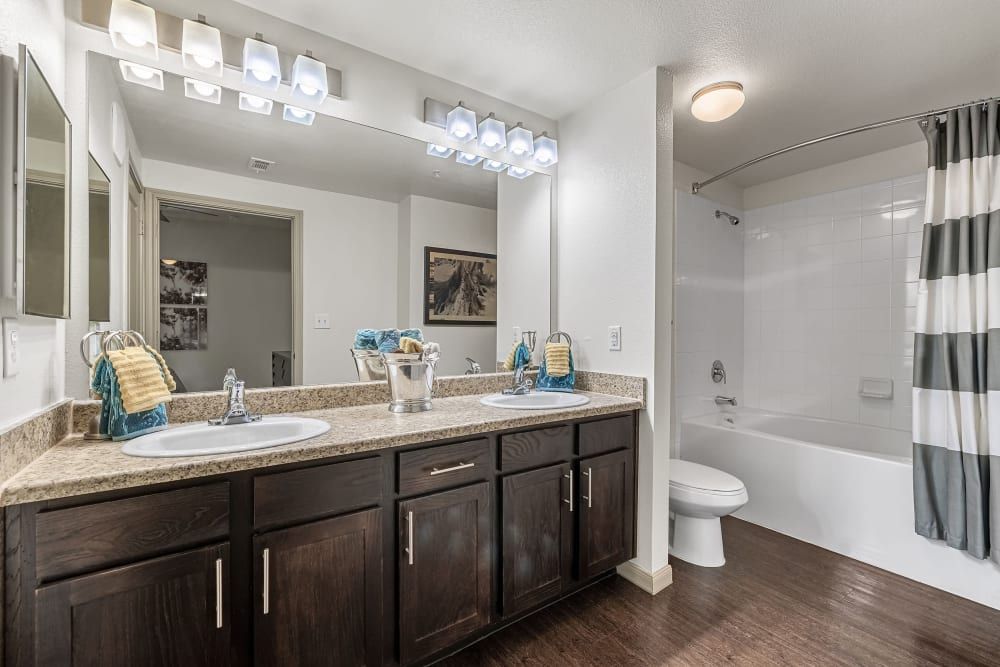 a bathroom with two sinks, a toilet, and a bathtub at Marquis on Lakeline in Cedar Park, TX.