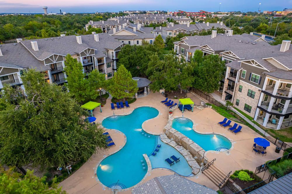 an aerial view of a large swimming pool surrounded by buildings at Marquis on Lakeline in Cedar Park, TX.