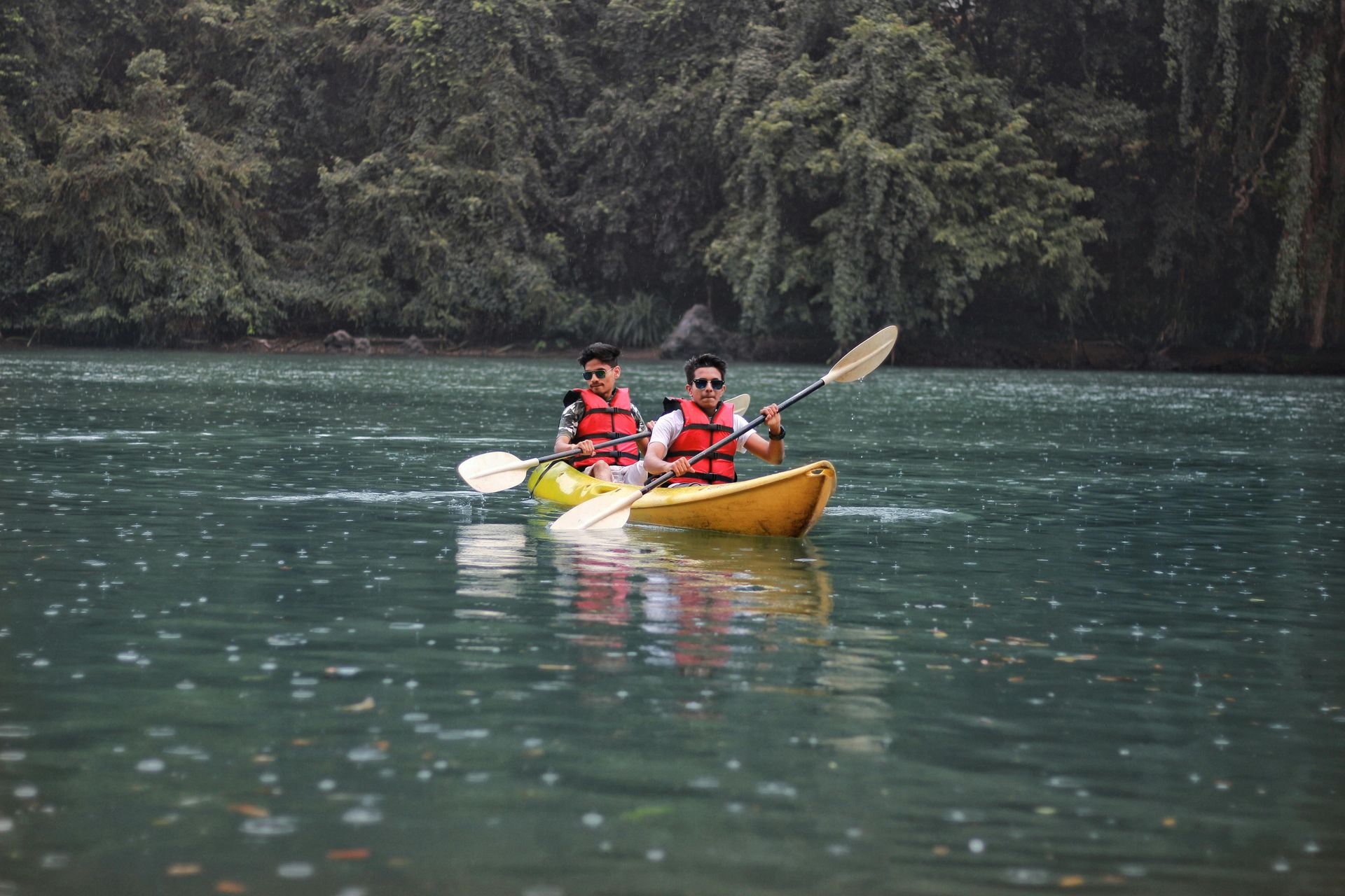 Two people are paddling kayaks on a lake.