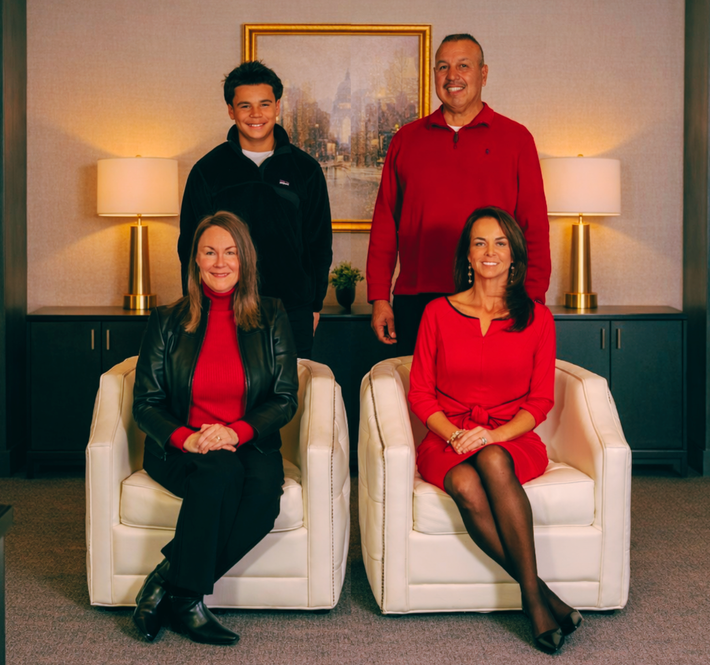 Group photo: five formally dressed people, including a child, against a blurred backdrop.