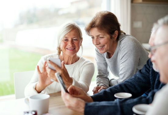 Young woman hugs older woman, both smiling broadly.