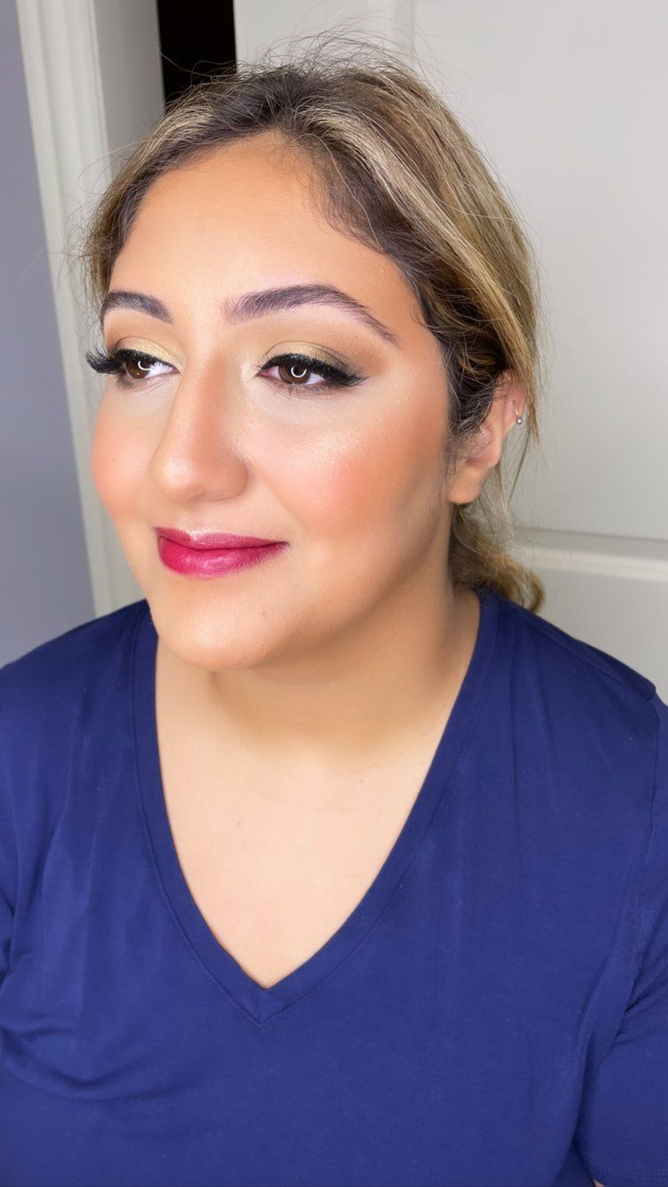 A woman wearing a blue shirt and red lipstick is looking at the camera.