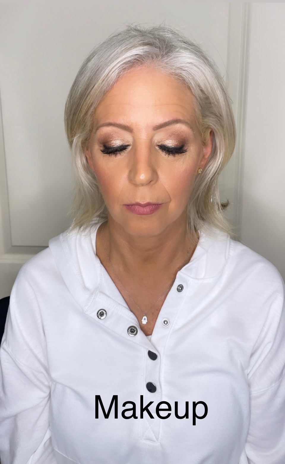 A woman is wearing makeup and a white shirt.