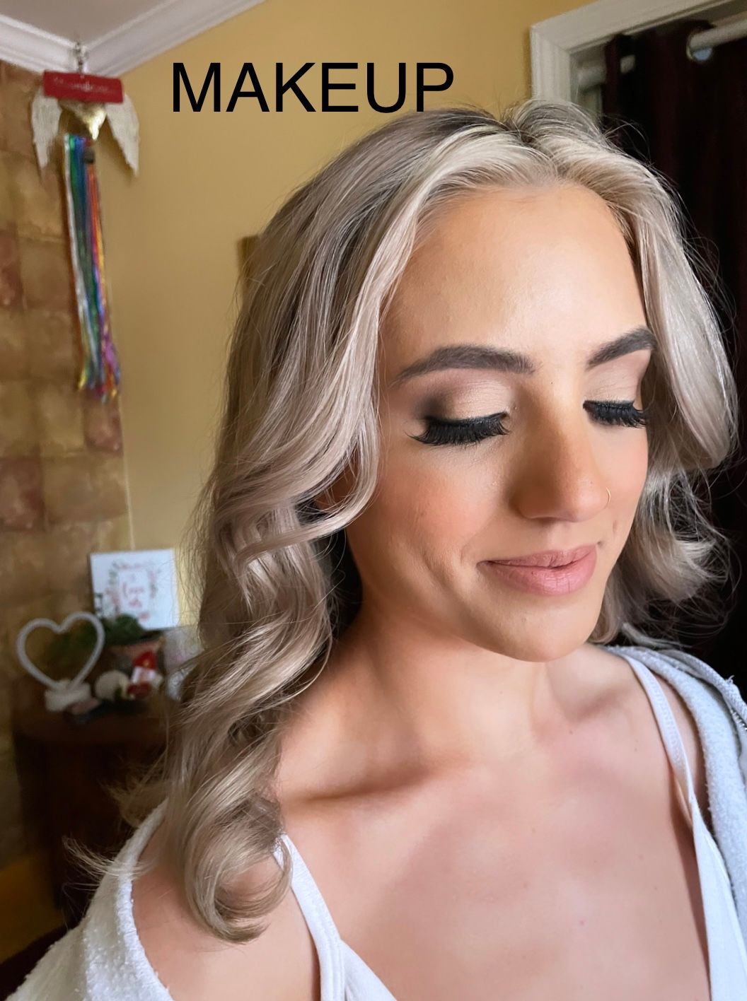 A woman is getting her makeup done in a room.
