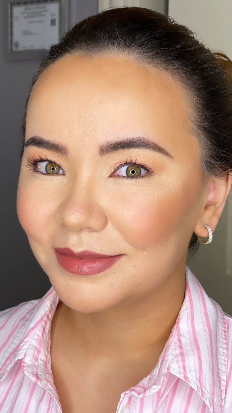A close up of a woman 's face wearing a pink striped shirt and earrings.