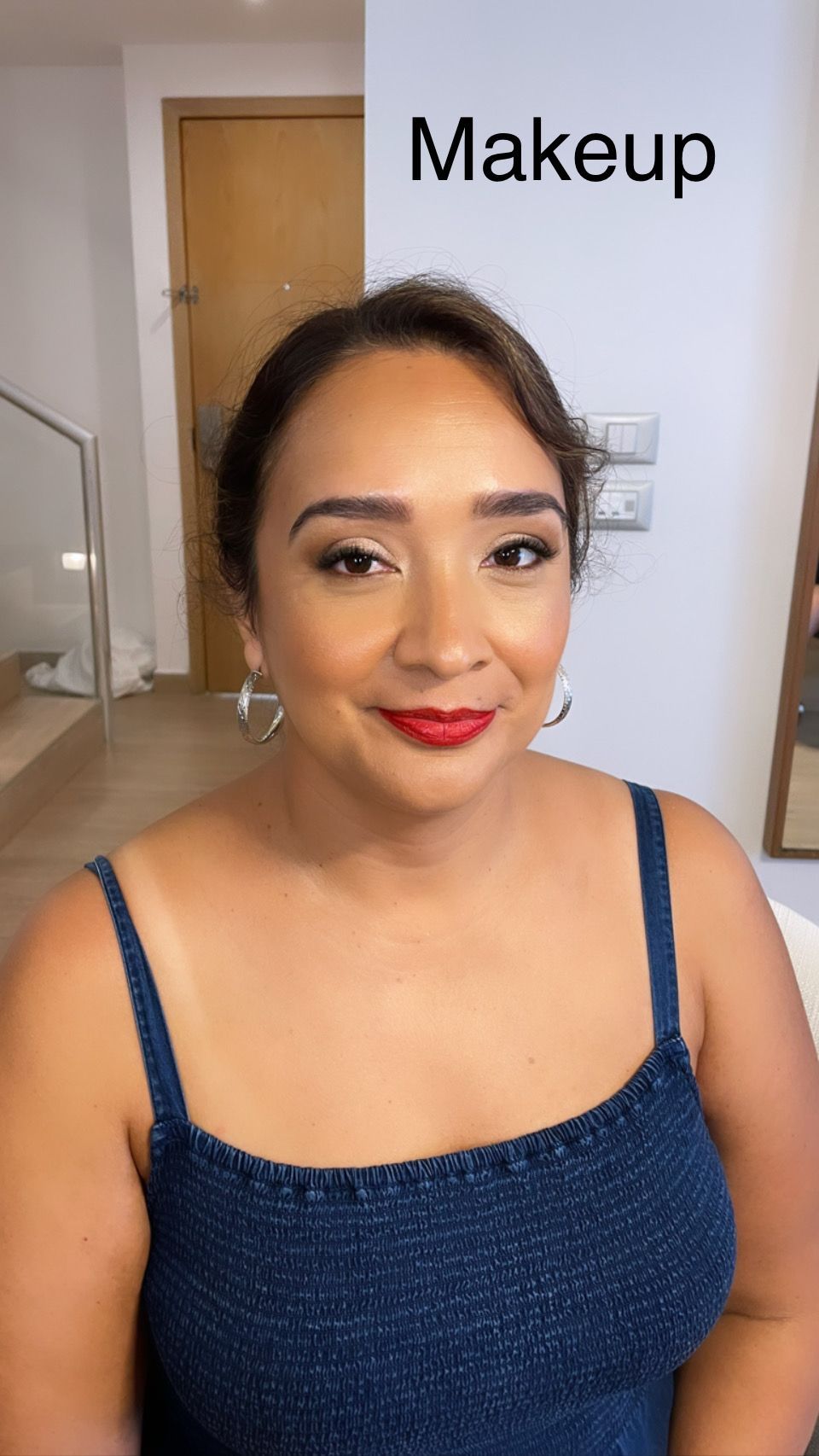 A woman is wearing a blue tank top and red lipstick.