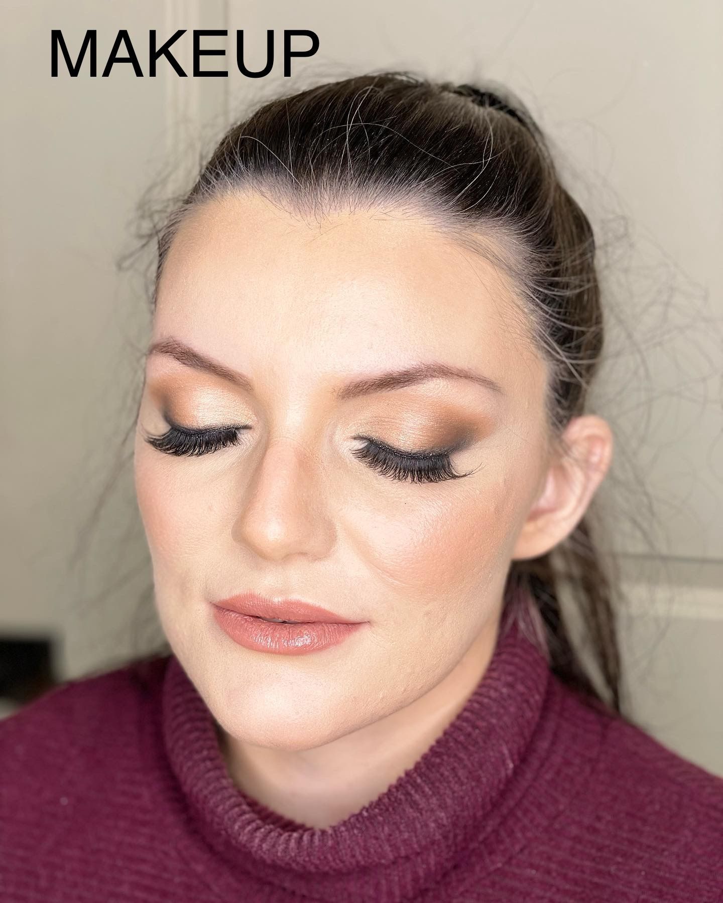 A woman with makeup on her face is wearing a purple sweater.