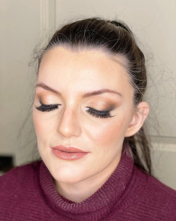 A close up of a woman wearing a purple sweater and makeup.
