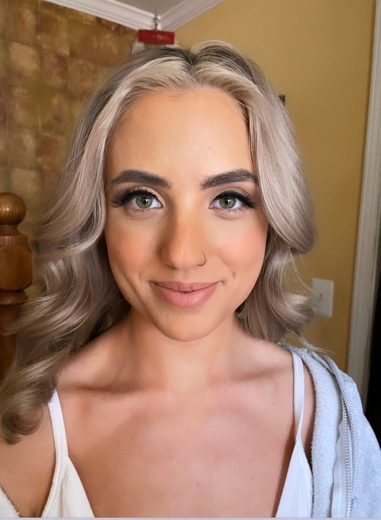 A woman with blonde hair and green eyes is smiling for the camera.