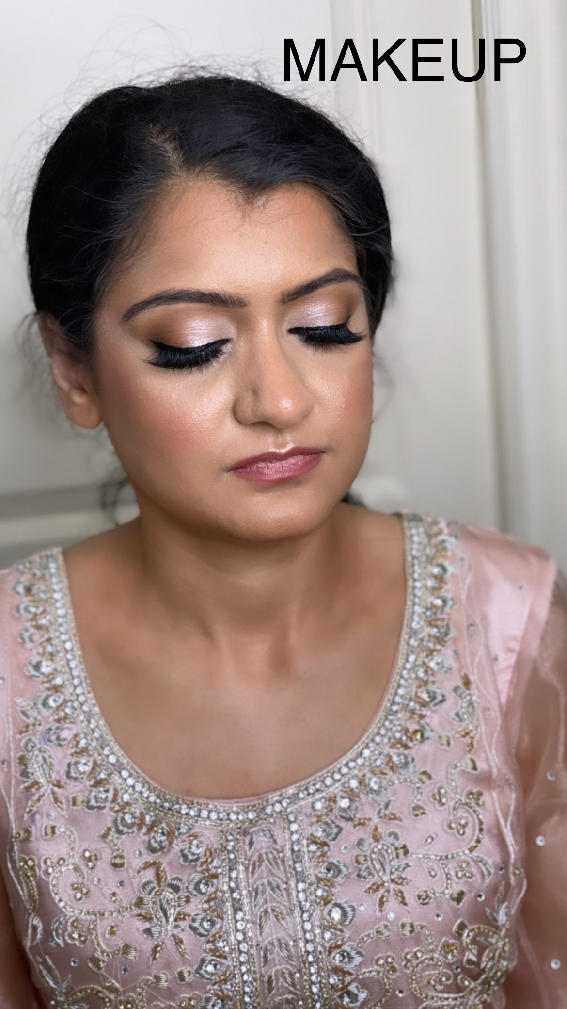 A woman in a pink dress is getting her makeup done.
