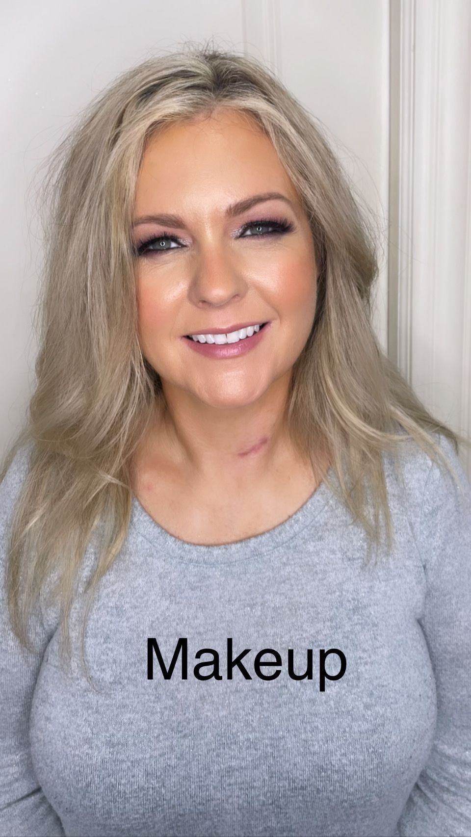 A woman wearing a grey shirt with the word makeup on it.