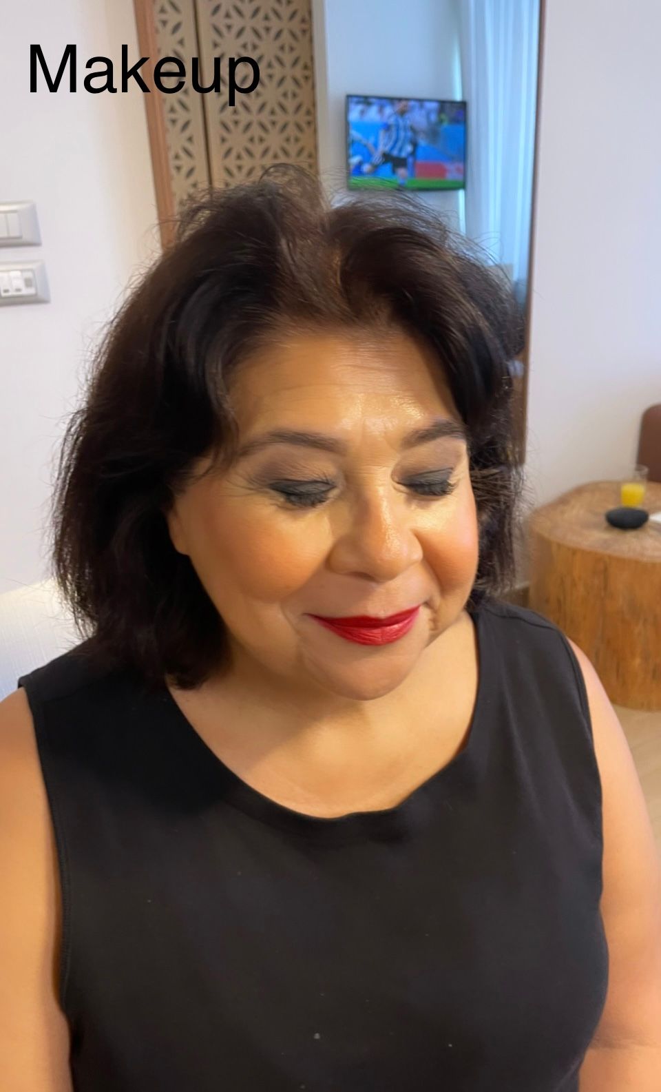 A woman is wearing red lipstick and a black tank top.