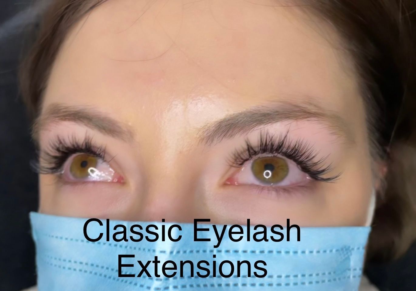 A close up of a woman wearing a mask with classic eyelash extensions.