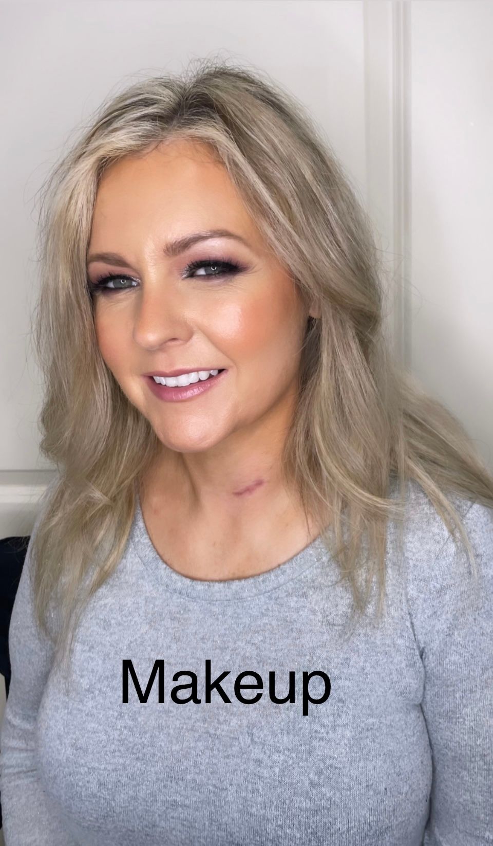 A woman wearing a gray shirt with the word makeup on it.
