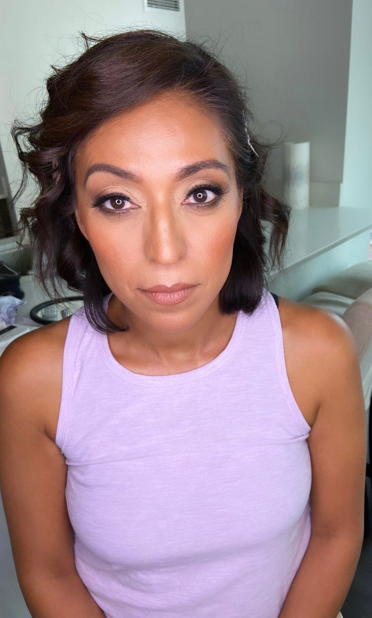 A woman in a purple tank top is looking at the camera.