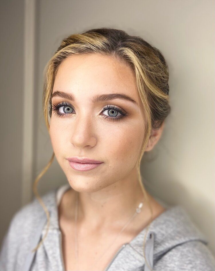 A close up of a woman 's face wearing a grey hoodie.