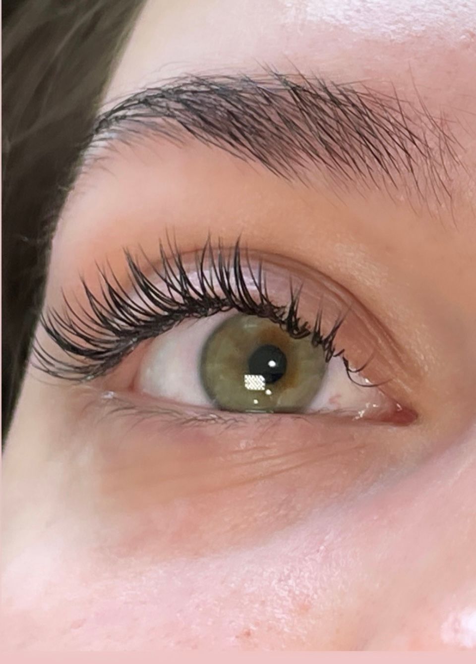 A close up of a woman 's green eye with long eyelashes.