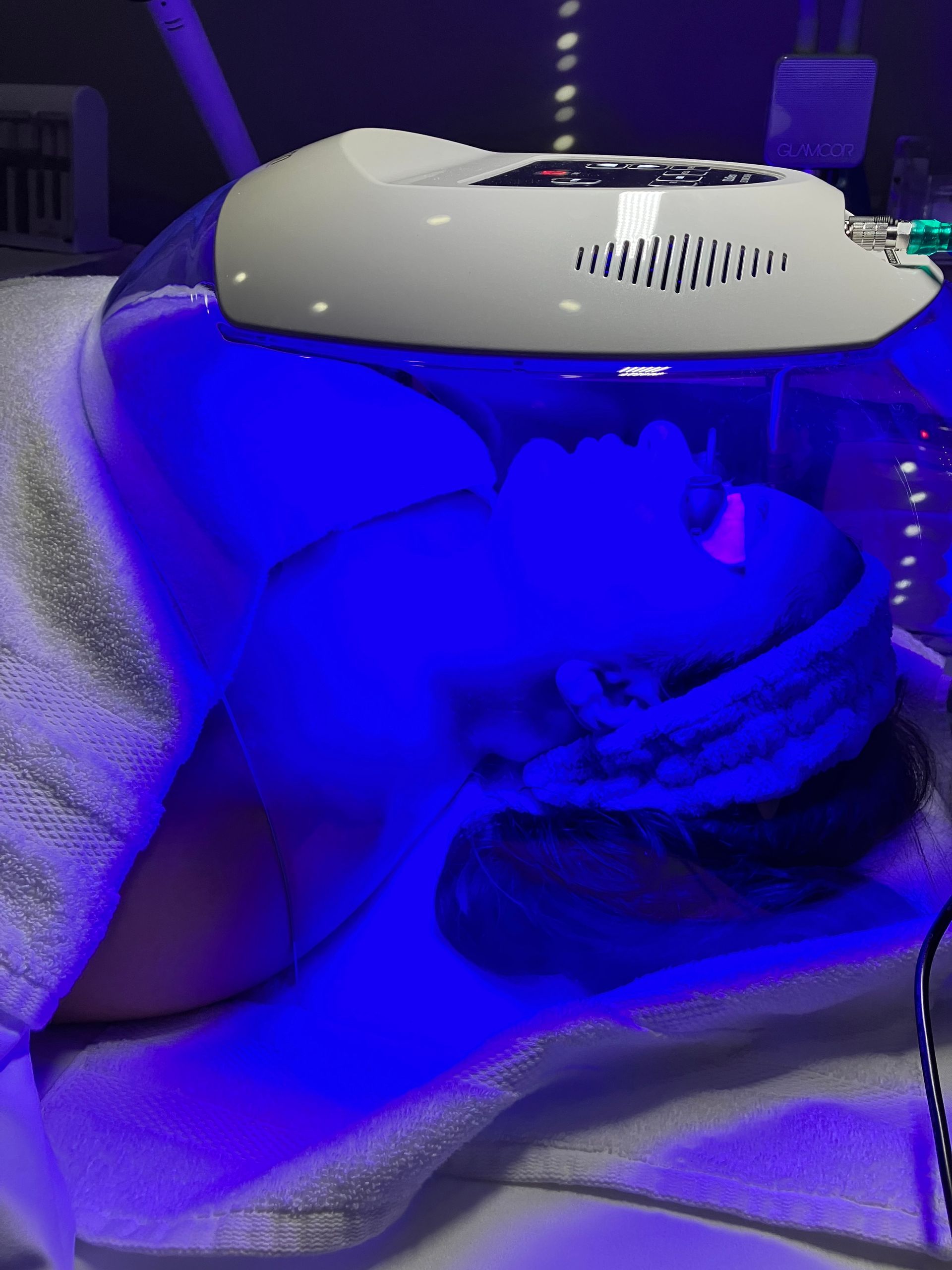 A person is getting a blue light treatment on their face.
