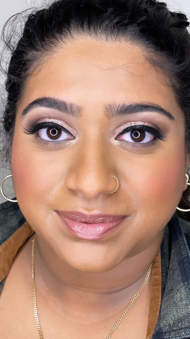 A close up of a woman 's face with makeup and a nose ring.