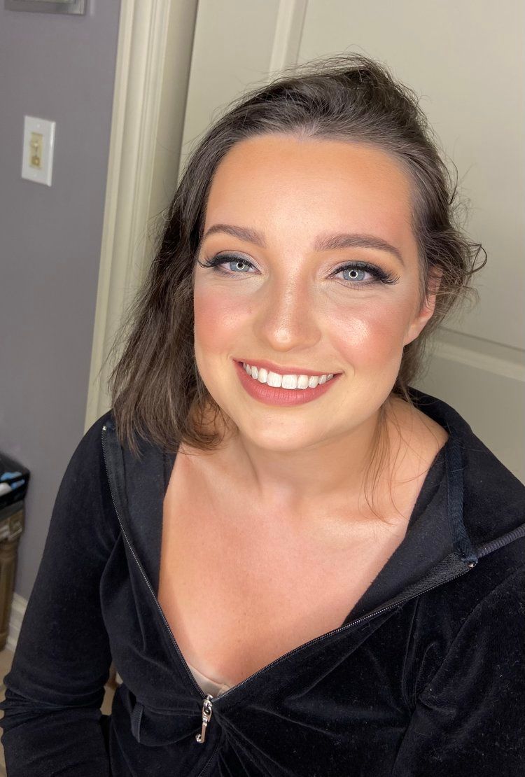 A woman in a black hoodie is smiling and looking at the camera.