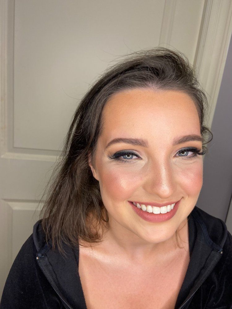 A close up of a woman 's face smiling in front of a door.