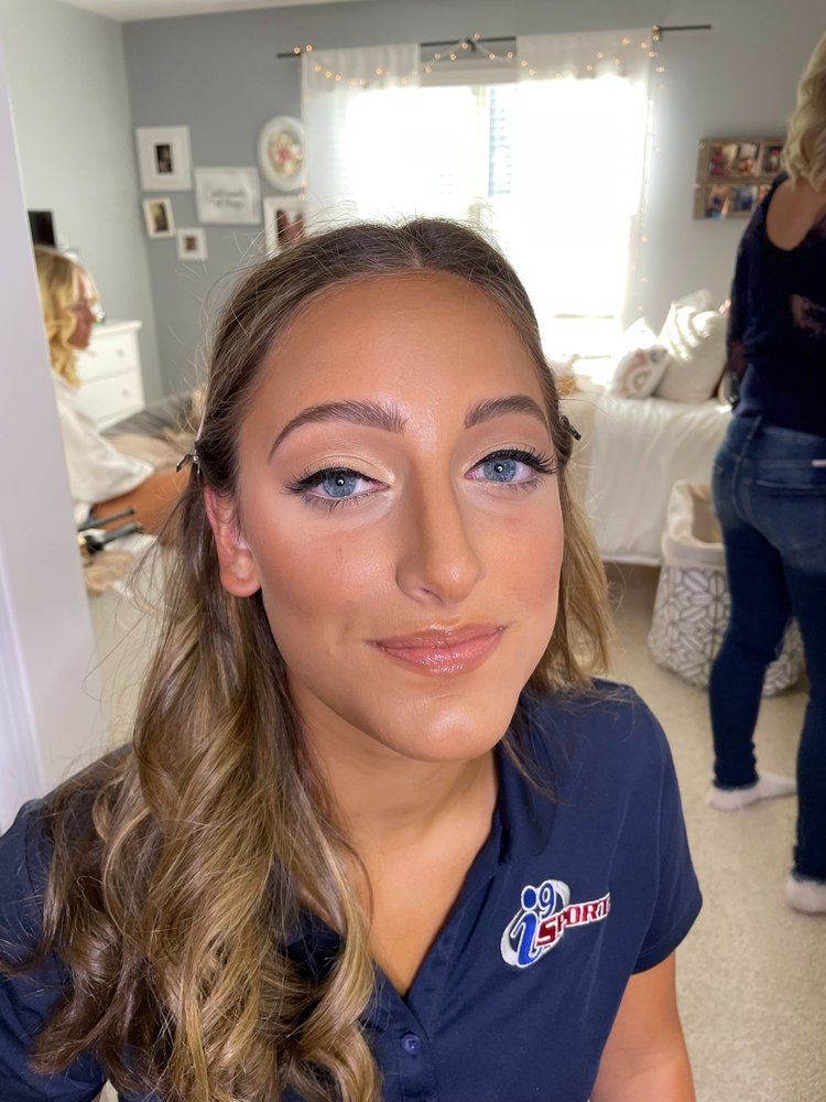 A woman wearing a blue shirt with a logo on it is standing in a room.