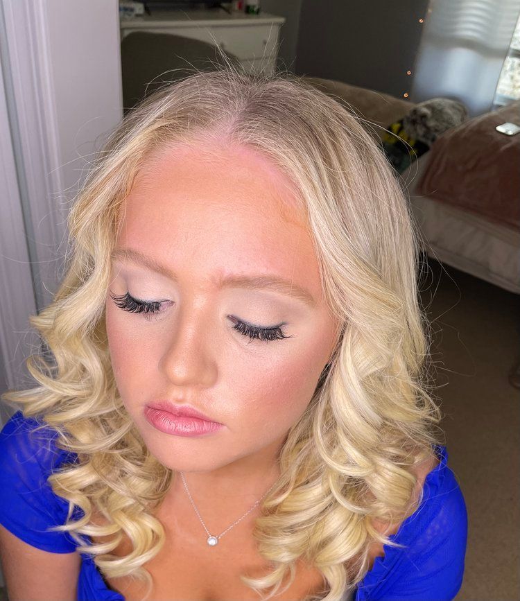 A woman with blonde hair and long eyelashes is wearing a blue shirt.