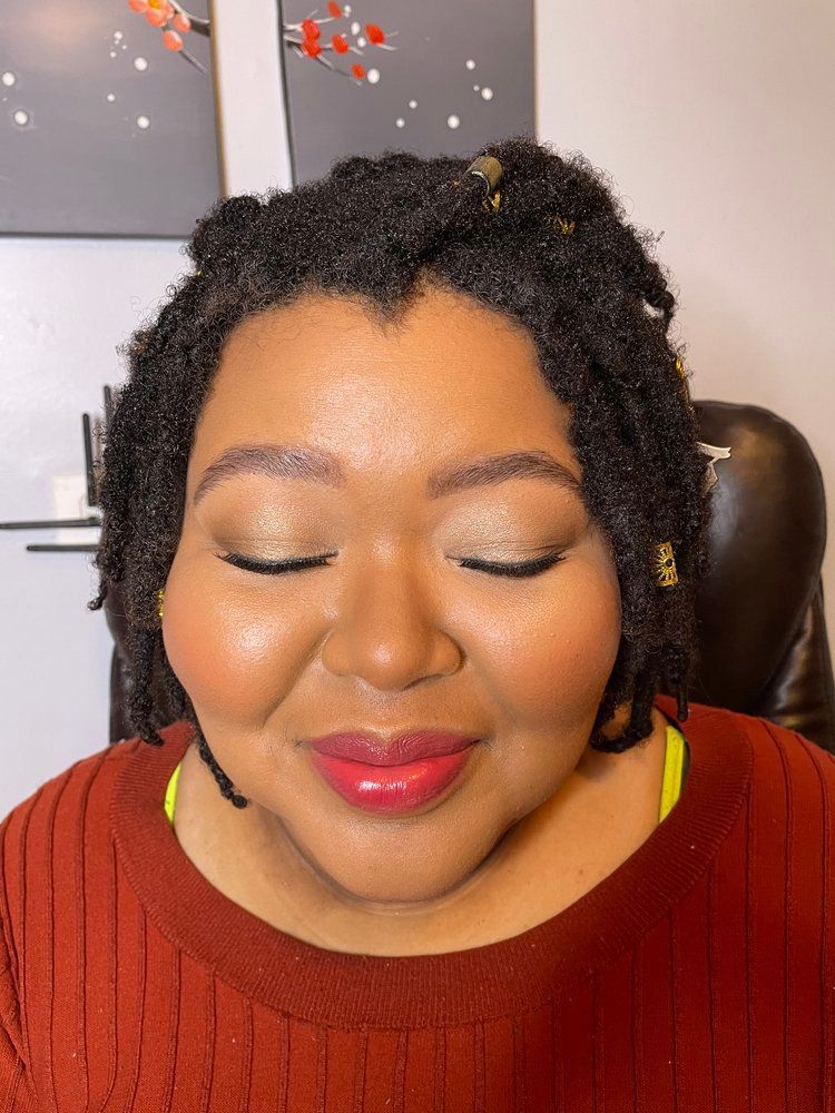 A woman with dreadlocks is wearing a red sweater and red lipstick.