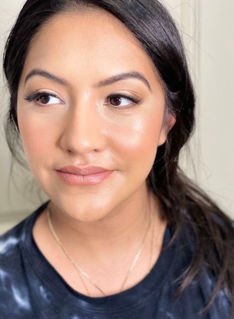 A close up of a woman 's face wearing a tie dye shirt and a necklace.