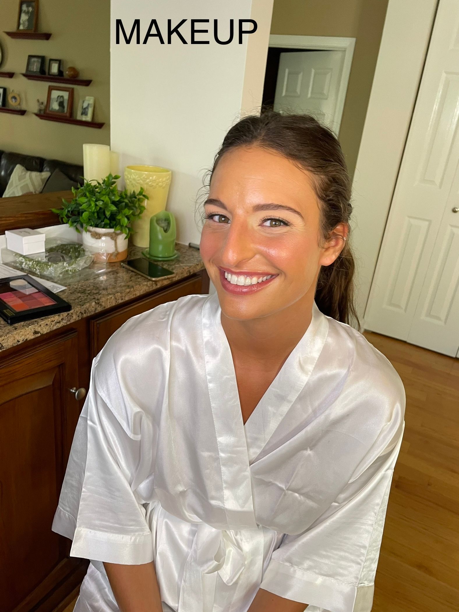 A woman in a white robe is smiling in front of a sign that says makeup