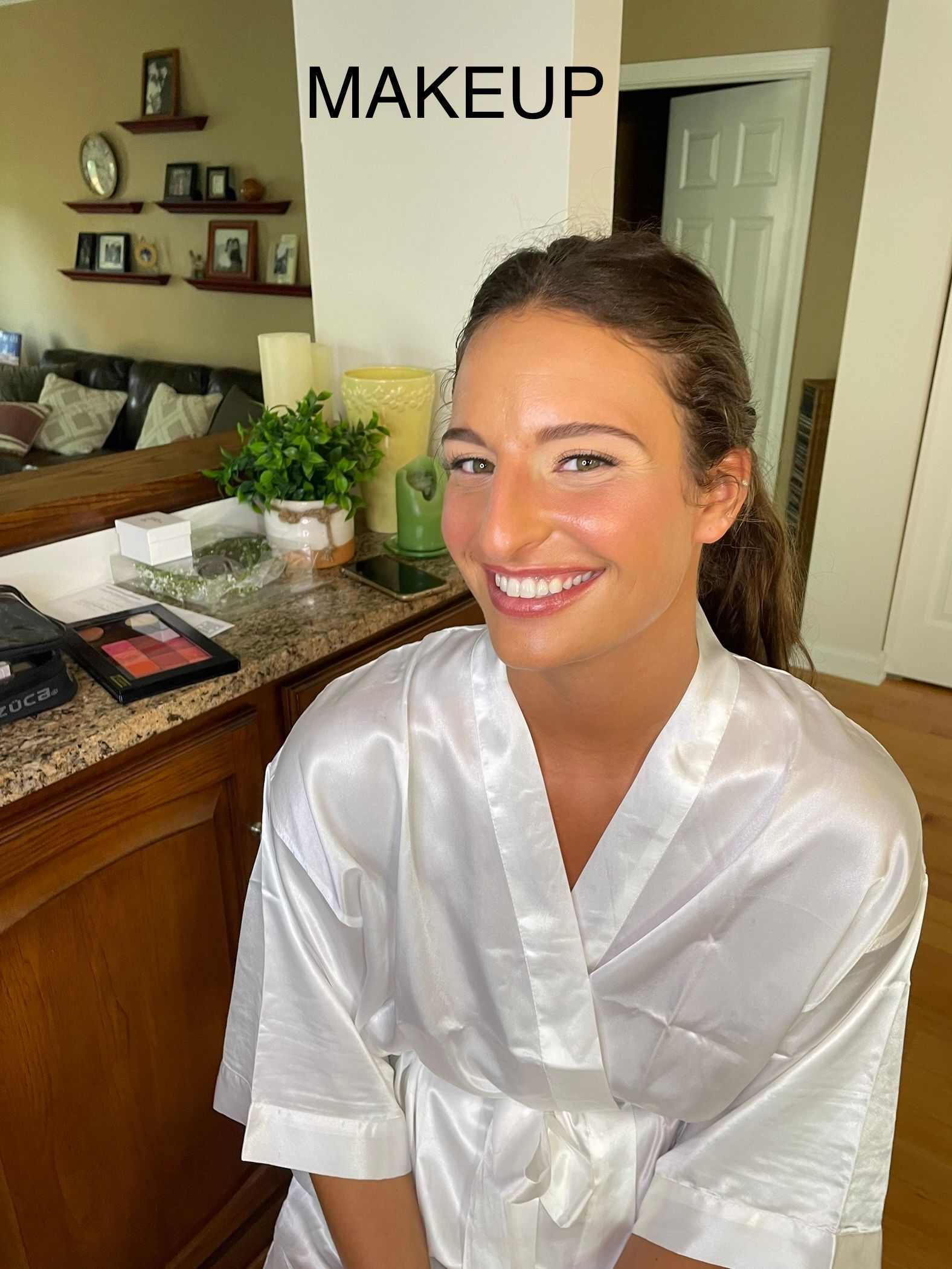 A woman in a white robe is smiling in front of a sign that says makeup.