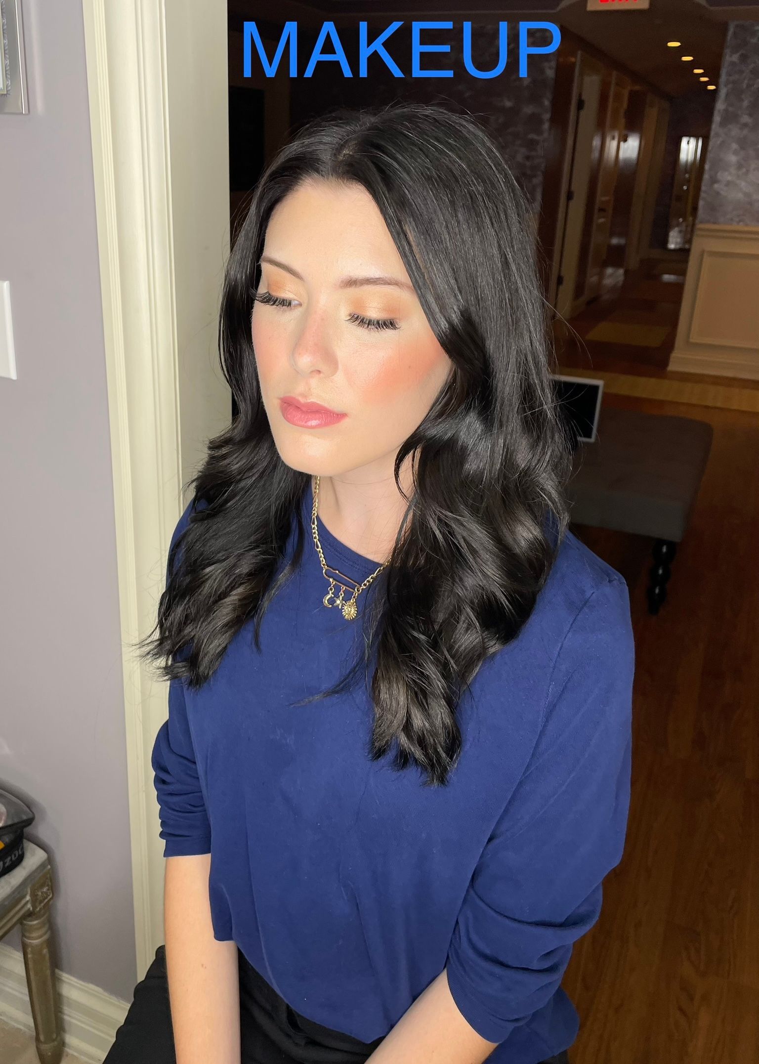 A woman is wearing a blue shirt and has makeup on her face.
