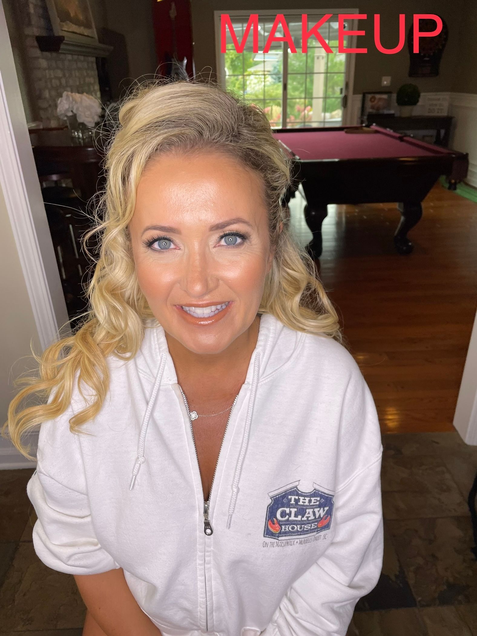 A woman in a white robe is sitting in front of a pool table.