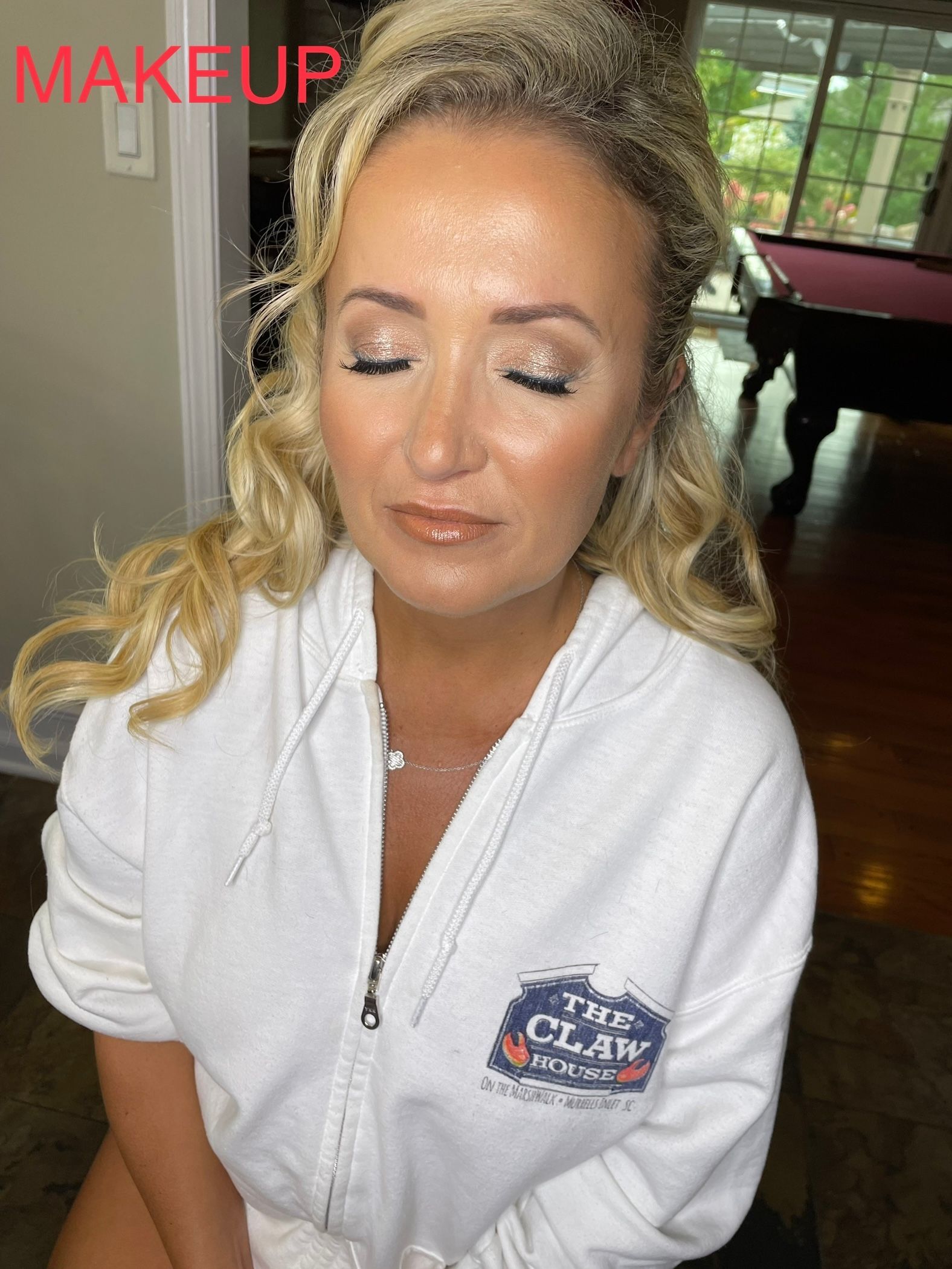 A woman in a white robe is sitting in front of a pool table.
