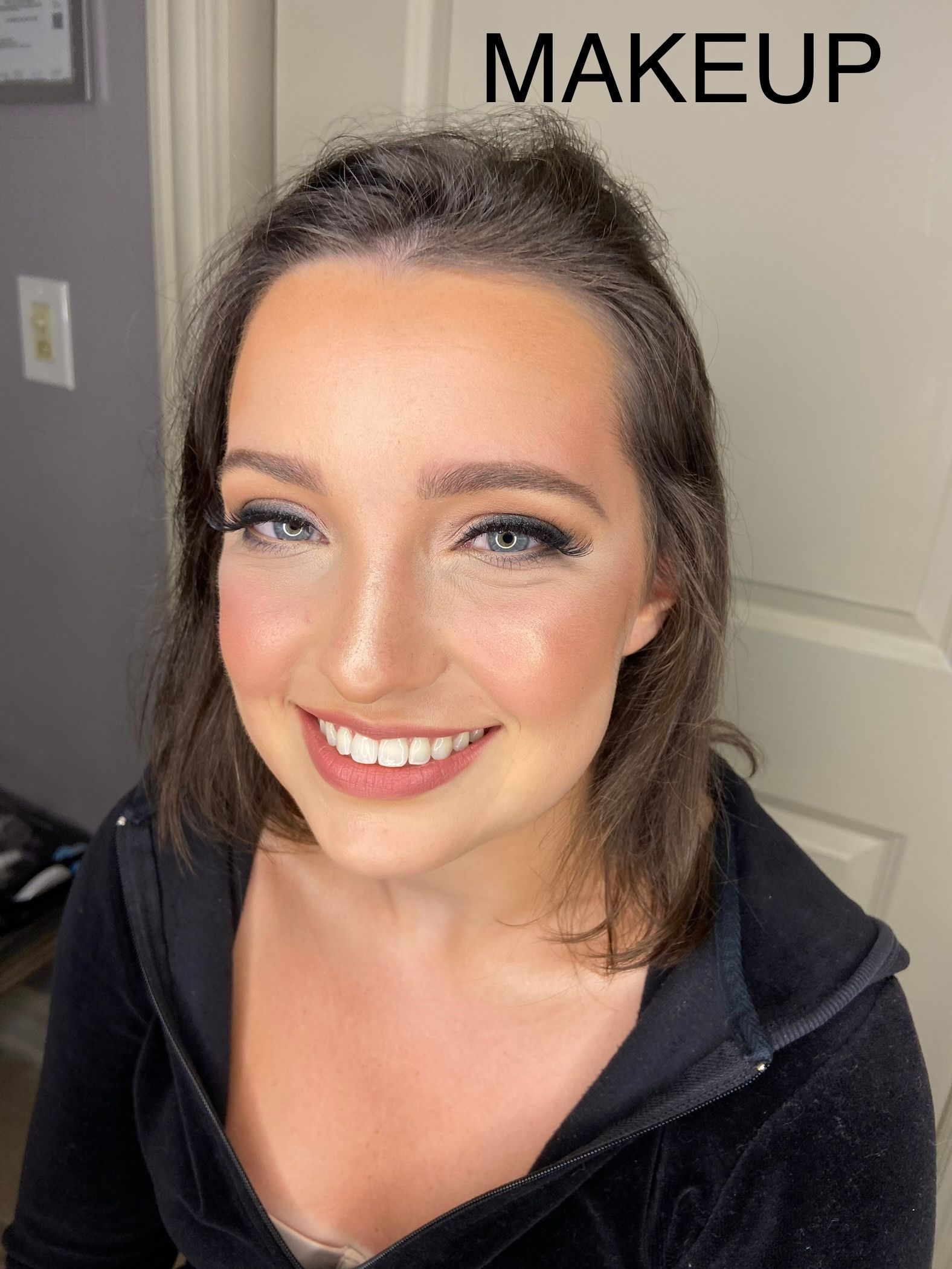 A woman is smiling in front of a sign that says makeup.